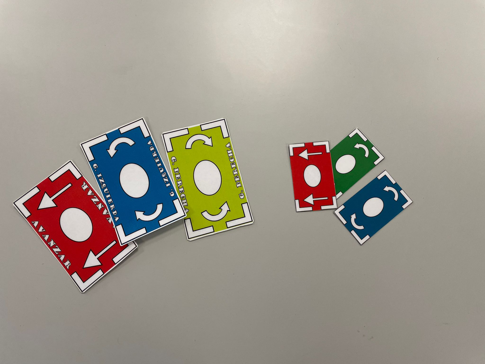 Se ven los distintos tipos de cartas que existen, las versiones iniciales y las actuales, las actuales son un tercio más grande que las primeras versiones, de izquierda a derec ha se ve, las tres cartas actuales, en orden avanzar, girar a la izquierda y girar a la derecha, luego le siguen las versiones antiguas, casa una tine un color identificativo, rojo para avanzar, azul para girar a la izquierda y verde para girar a la derecha